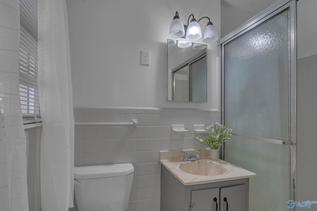 bathroom featuring a shower with door, vanity, tile walls, and toilet