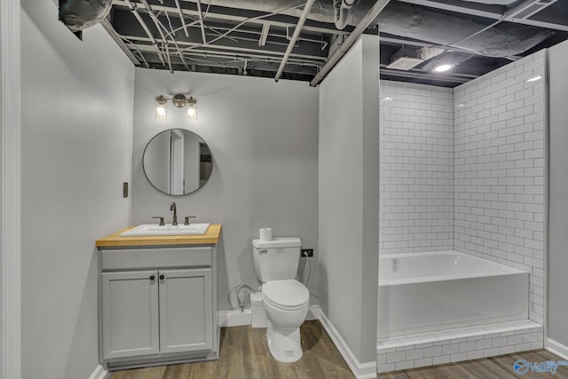 full bathroom featuring hardwood / wood-style flooring, tiled shower / bath, vanity, and toilet