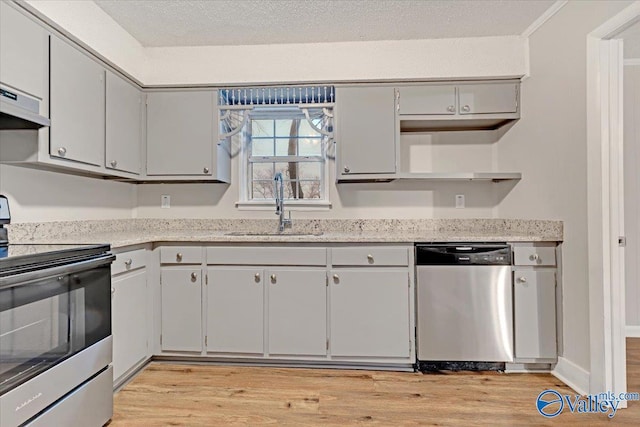 kitchen featuring a textured ceiling, stainless steel appliances, light hardwood / wood-style flooring, and sink