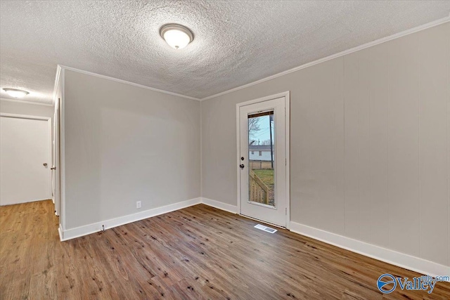 empty room featuring a textured ceiling, ornamental molding, and light hardwood / wood-style floors