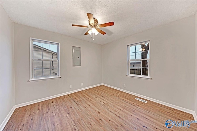 spare room featuring ceiling fan, a textured ceiling, electric panel, and light wood-type flooring