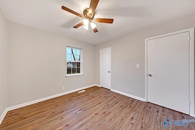 empty room with hardwood / wood-style flooring, a textured ceiling, and ceiling fan