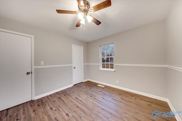 spare room featuring a textured ceiling, ceiling fan, and light hardwood / wood-style floors