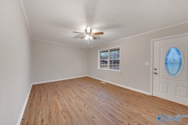 foyer entrance featuring ceiling fan, ornamental molding, a textured ceiling, and light hardwood / wood-style flooring