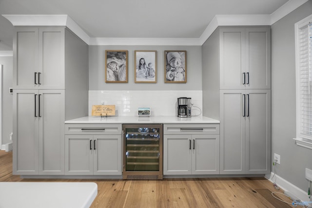 bar with wine cooler, backsplash, gray cabinetry, and light hardwood / wood-style floors