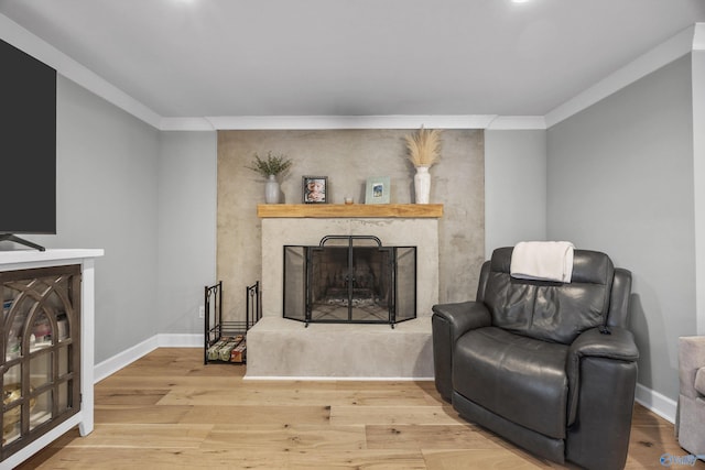 sitting room with ornamental molding and light wood-type flooring