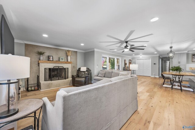 living room with light hardwood / wood-style flooring, ceiling fan, and crown molding