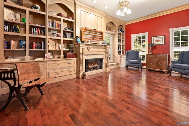 sitting room featuring built in features, crown molding, dark hardwood / wood-style floors, and a high end fireplace