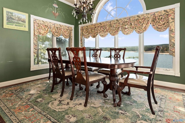 dining space with a water view, hardwood / wood-style floors, a wealth of natural light, and ornamental molding