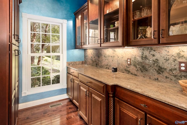 bar featuring dark hardwood / wood-style floors, light stone counters, and tasteful backsplash