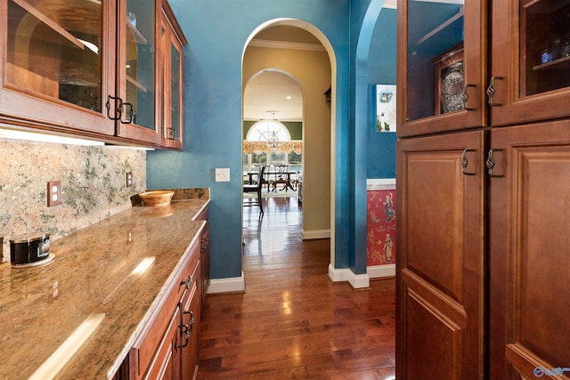 kitchen featuring ornamental molding, dark hardwood / wood-style flooring, tasteful backsplash, and light stone counters