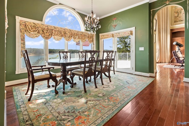 dining space featuring a water view, dark hardwood / wood-style flooring, ornamental molding, and plenty of natural light