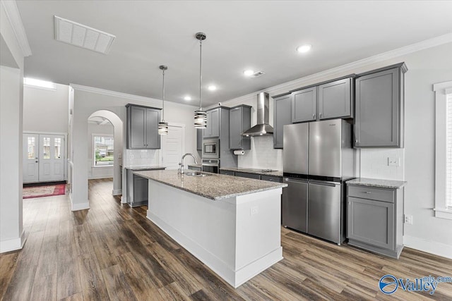 246 Tybee Dr, Madison, AL 35756 - kitchen with wall chimney range hood, appliances with stainless steel finishes, arched walkways, a sink, and gray cabinetry