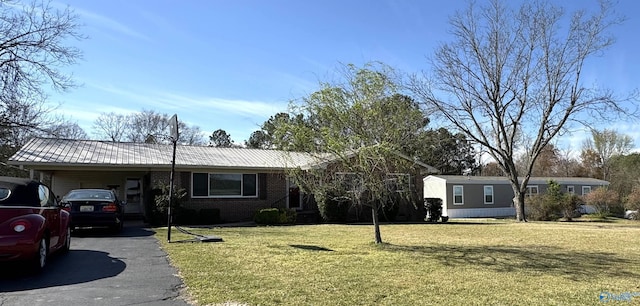ranch-style house with metal roof, an attached carport, brick siding, a front lawn, and driveway