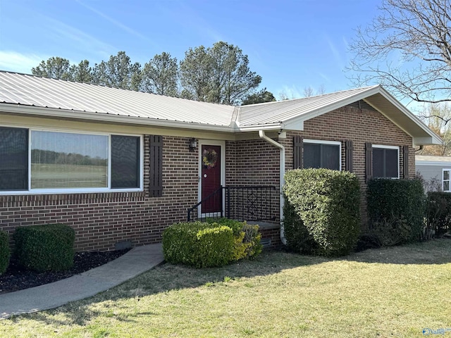 single story home featuring a front lawn, metal roof, and brick siding