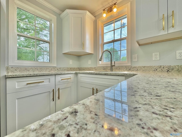 kitchen featuring a wealth of natural light, white cabinetry, crown molding, and sink