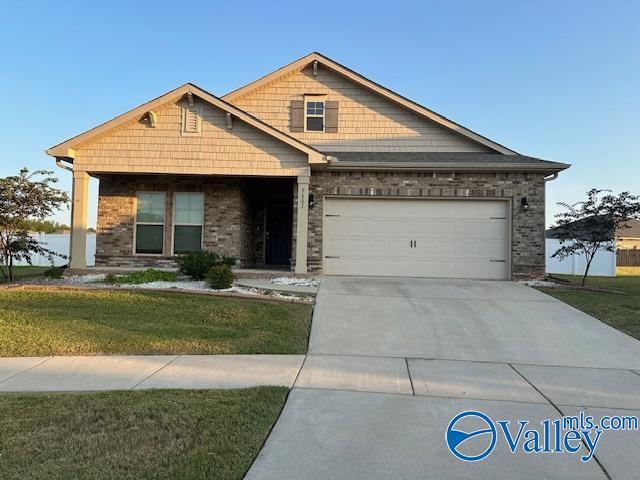 view of front of house with concrete driveway, brick siding, a front lawn, and an attached garage