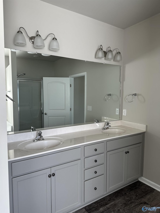 bathroom featuring double vanity, an enclosed shower, a sink, and wood finished floors