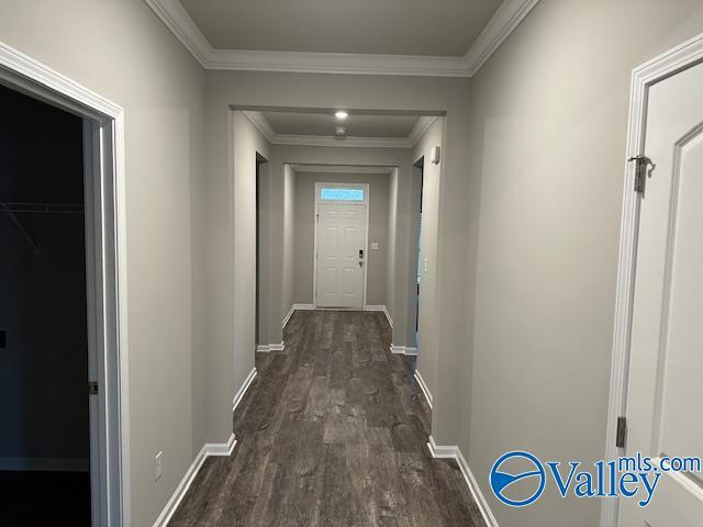 hallway with ornamental molding, dark wood-style flooring, and baseboards