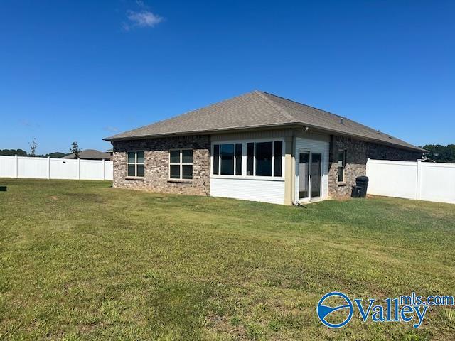 back of house featuring a fenced backyard and a lawn