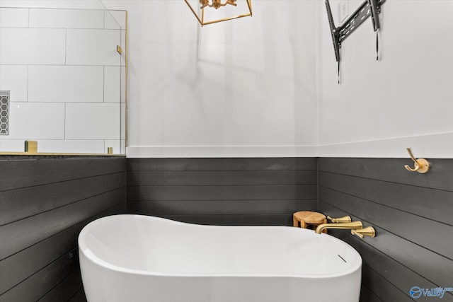 bathroom featuring wooden walls and a bathing tub