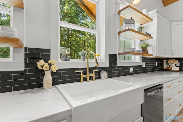 kitchen with sink, dishwasher, white cabinetry, backsplash, and light stone countertops