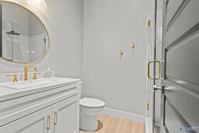 bathroom with vanity, wood-type flooring, toilet, and a shower with shower door