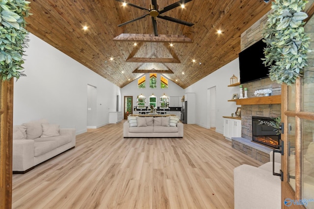 living room featuring a stone fireplace, high vaulted ceiling, light hardwood / wood-style floors, wooden ceiling, and beam ceiling