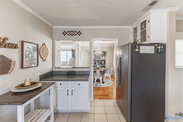 kitchen featuring visible vents, dark countertops, glass insert cabinets, freestanding refrigerator, and white cabinetry