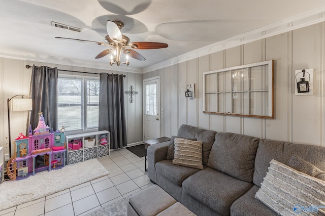 living area with light tile patterned floors, ornamental molding, visible vents, and a ceiling fan