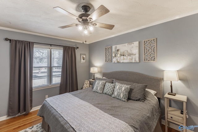 bedroom with ceiling fan, ornamental molding, wood finished floors, and baseboards