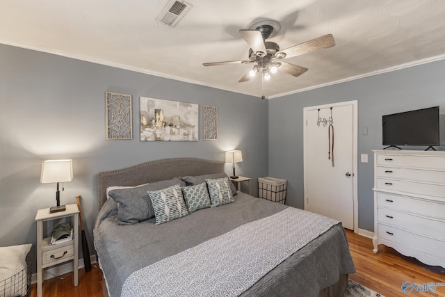 bedroom featuring ornamental molding, visible vents, ceiling fan, and wood finished floors