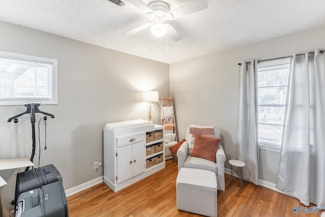 living area with light wood-type flooring, a wealth of natural light, and baseboards