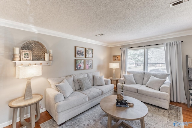 living room with a textured ceiling, ornamental molding, wood finished floors, and visible vents