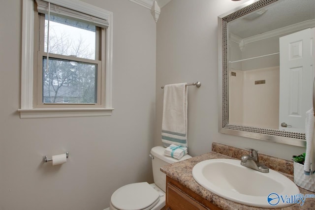 bathroom with vanity, crown molding, toilet, and walk in shower