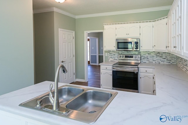 kitchen featuring sink, crown molding, appliances with stainless steel finishes, white cabinetry, and decorative backsplash