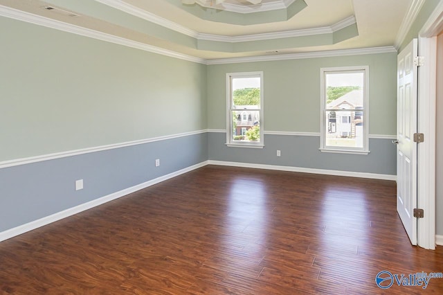 empty room with dark hardwood / wood-style flooring, crown molding, and a raised ceiling