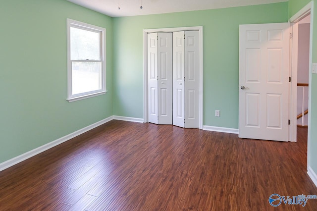 unfurnished bedroom with dark wood-type flooring and a closet