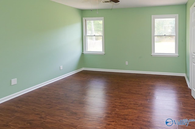 empty room featuring ceiling fan, dark wood-type flooring, and a healthy amount of sunlight