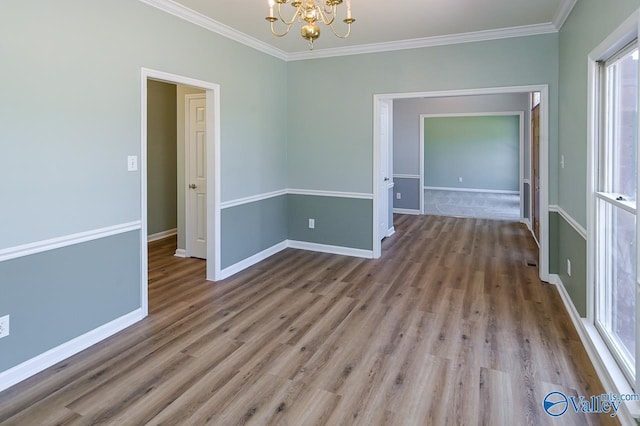 empty room featuring an inviting chandelier, ornamental molding, and light wood-type flooring