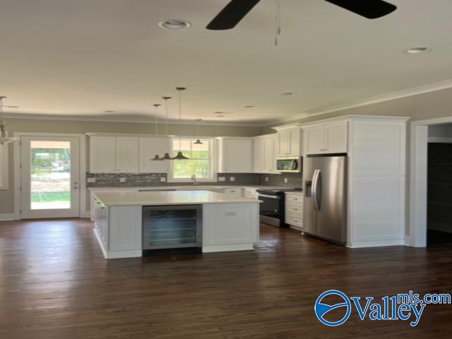 kitchen featuring stainless steel appliances, beverage cooler, a kitchen island, ceiling fan, and dark hardwood / wood-style floors