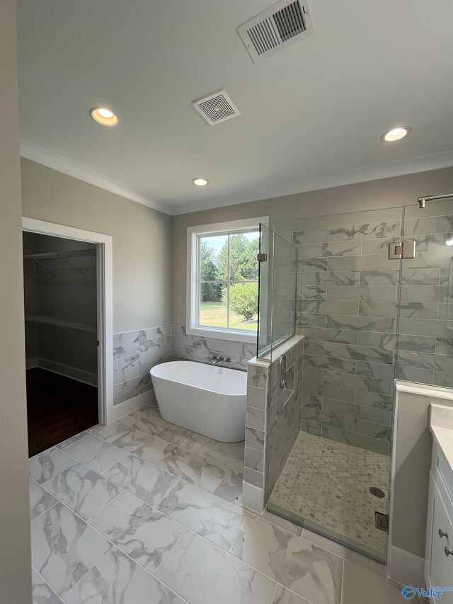 bathroom with tile walls, separate shower and tub, ornamental molding, and vanity