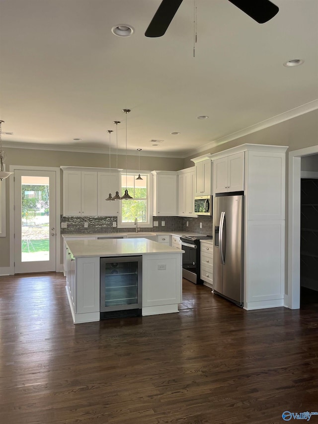 kitchen with a kitchen island, wine cooler, appliances with stainless steel finishes, hanging light fixtures, and ceiling fan