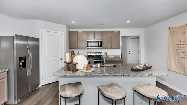 18882 Wicklow Cir, Athens, AL 35613 - kitchen featuring stainless steel appliances, dark wood-type flooring, a sink, a breakfast bar area, and light stone countertops