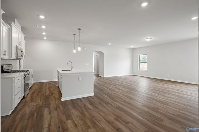 kitchen with pendant lighting, a kitchen island with sink, dark wood-type flooring, white cabinets, and appliances with stainless steel finishes