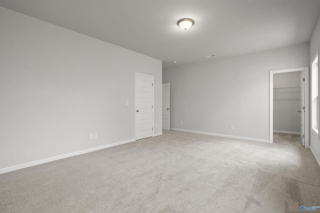 unfurnished bedroom featuring light carpet, a spacious closet, and a closet