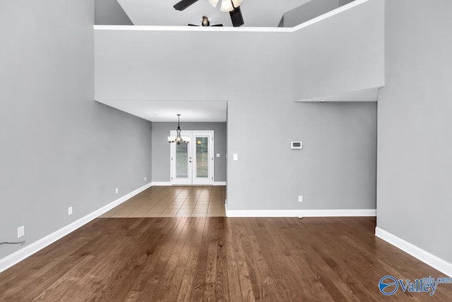 unfurnished living room with hardwood / wood-style floors and ceiling fan with notable chandelier