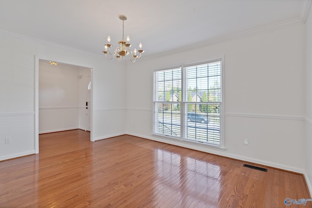 spare room featuring a notable chandelier, ornamental molding, and hardwood / wood-style flooring