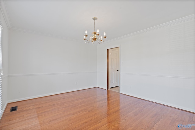 spare room with light hardwood / wood-style floors, ornamental molding, and a chandelier