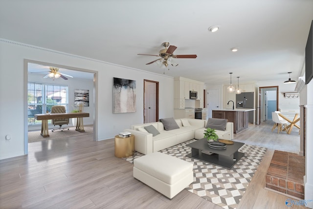 living room with ceiling fan, ornamental molding, and light hardwood / wood-style flooring